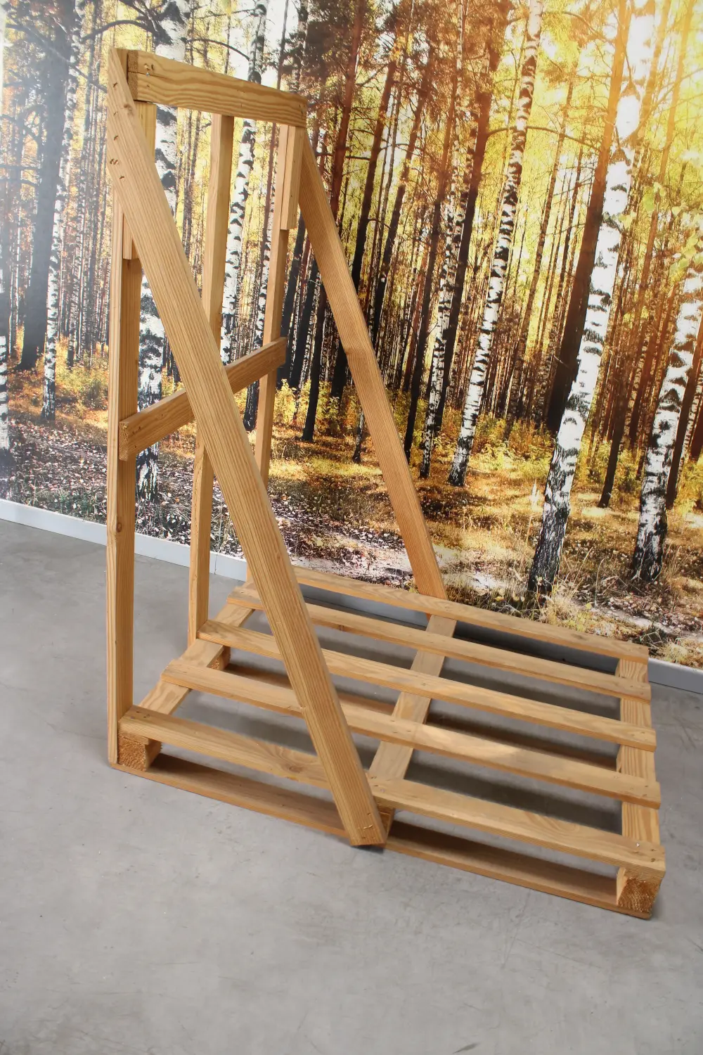 Chevalet en L en bois vu de profil, devant un décor de bouleaux