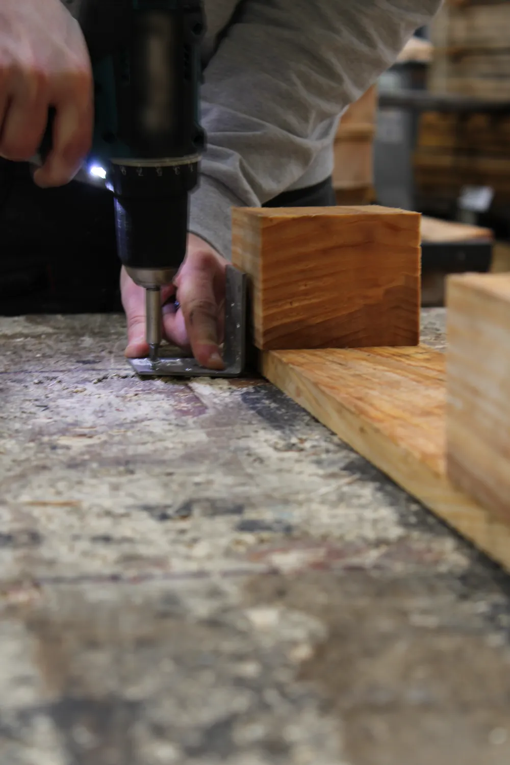 Mains d’un opérateur vissant une équerre métallique sur une pièce de bois